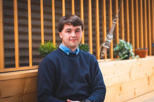 Daniel James, NMITE MEng Integrated Engineering student sitting outside NMITE building