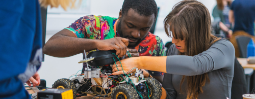 Male and female student working together on a small autonomous vehicle